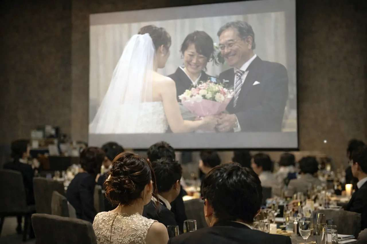 スクリーンに写った新婦から両親への花束贈呈シーン